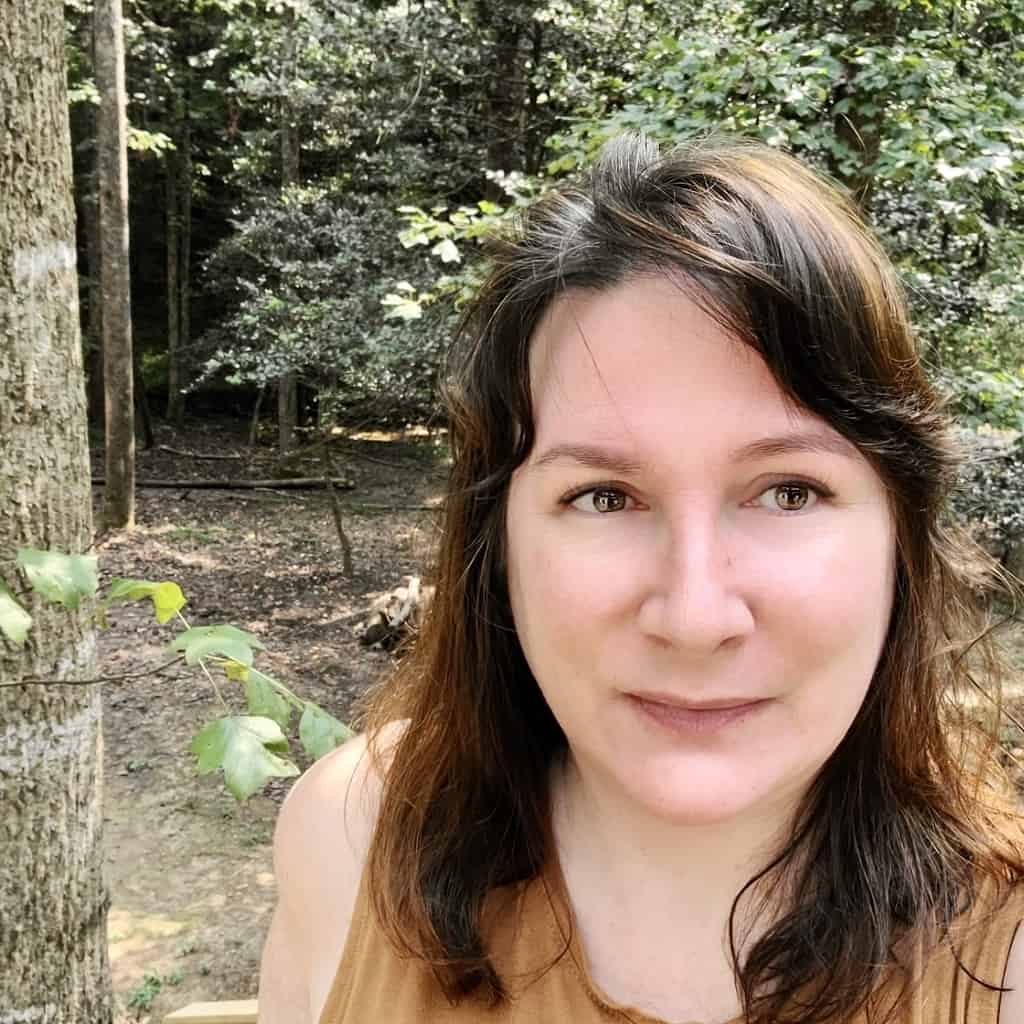 A photo of Melissa Bining standing in front of trees.