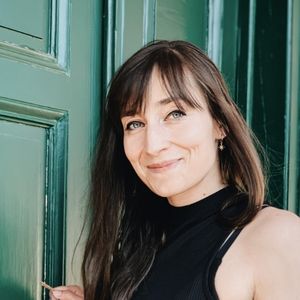 A photo of Katharina Geissler-Evans standing in front of a green door.